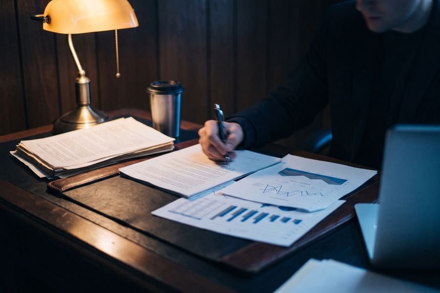 Printed pitch deck pages and revenue charts under a desk lamp