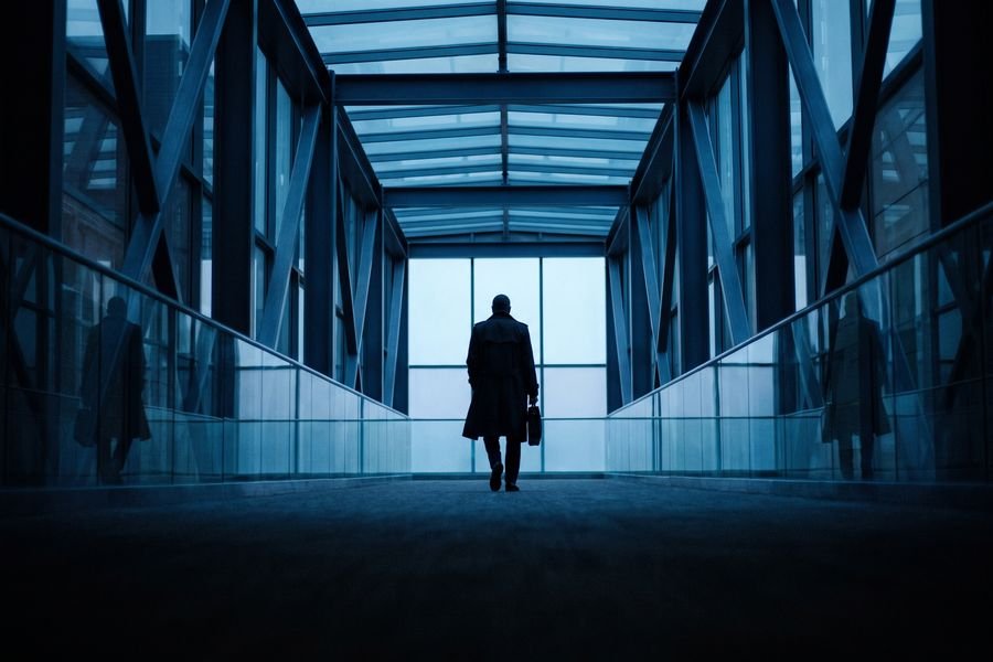 A silhouetted figure walking through a glass medical campus walkway